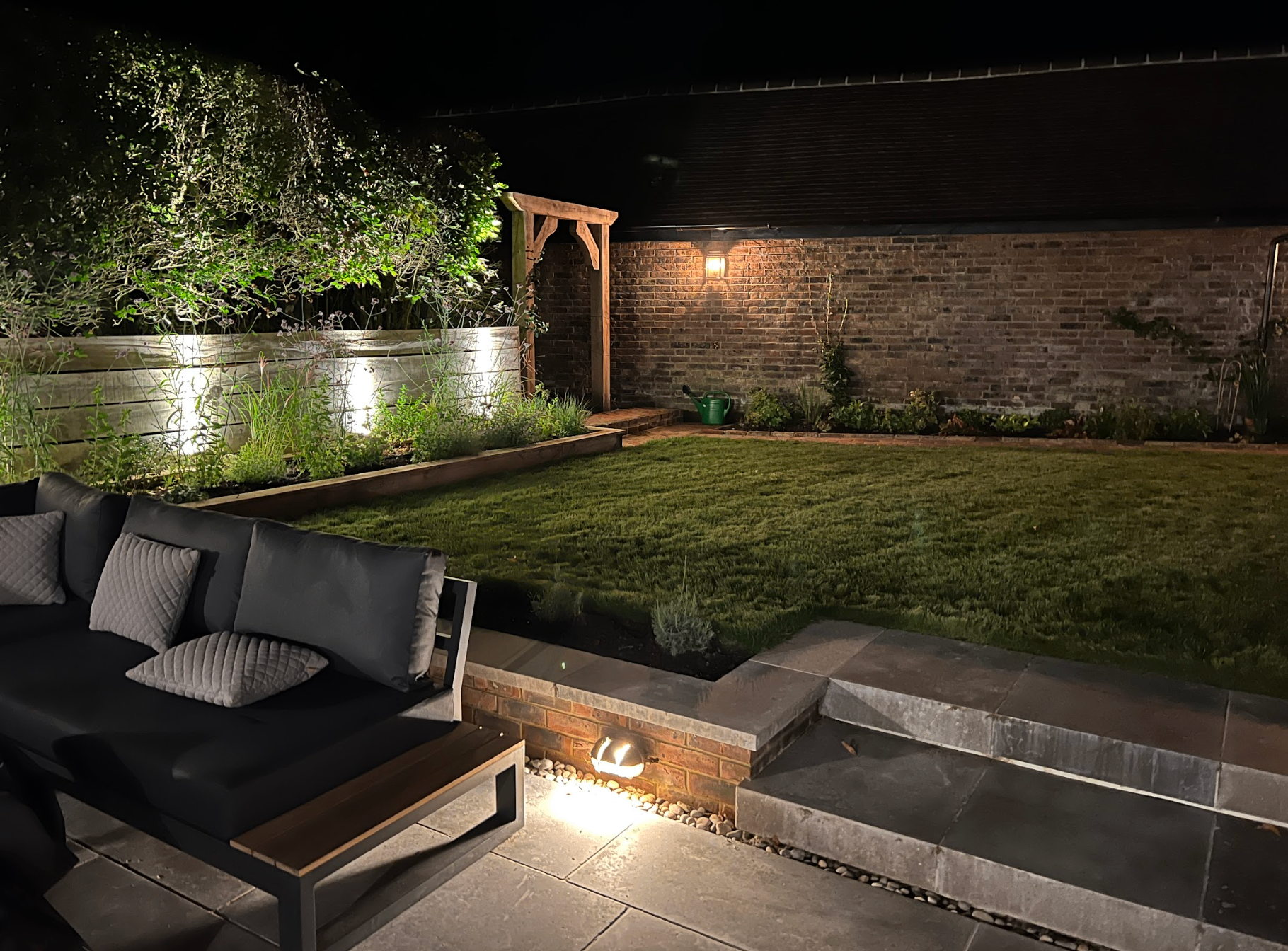 Bespoke garden at night with feature lighting, raised beds and patio lounge