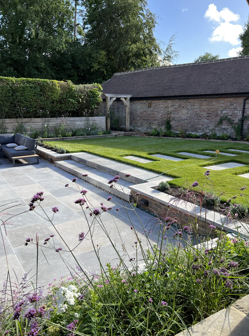 Manicured English country garden with striped lawn and mature trees